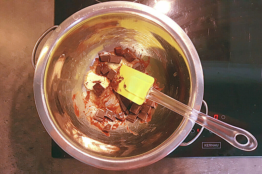rozpuszczanie masła z czekoladą w kąpieli wodnej, garnek, płyta indulcyjna, szpatułka, czekolada, masło, miska