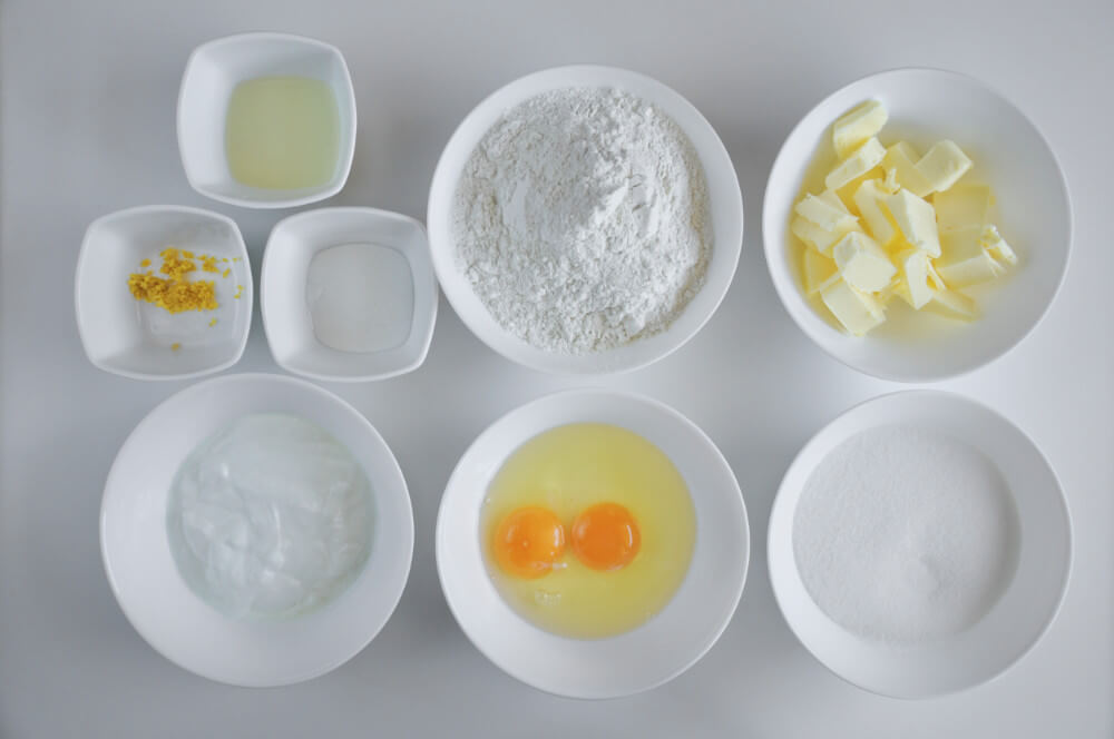 składniki na ucierane ciasto cytrynowe: masło, mąka, jaja, cukier, sok i skórka z cytryny, proszek do pieczenia