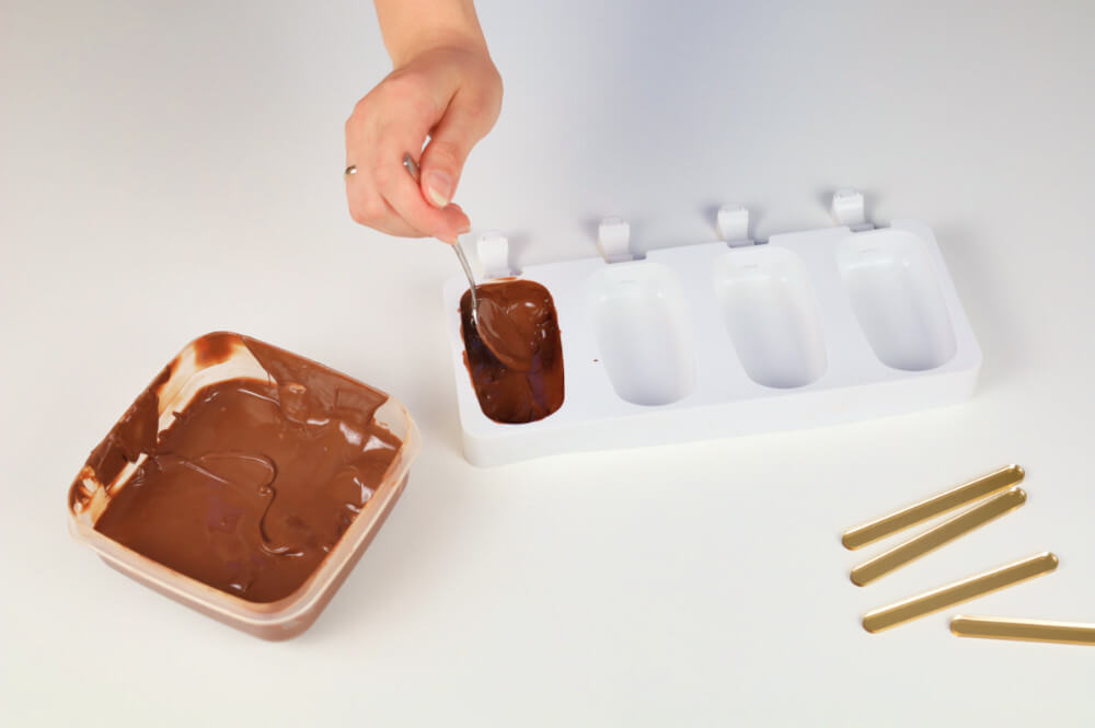 przygotowanie domowych lodów magnum - wypełnianie formy silikonowej formy na lody rozpuszczoną czekoladą