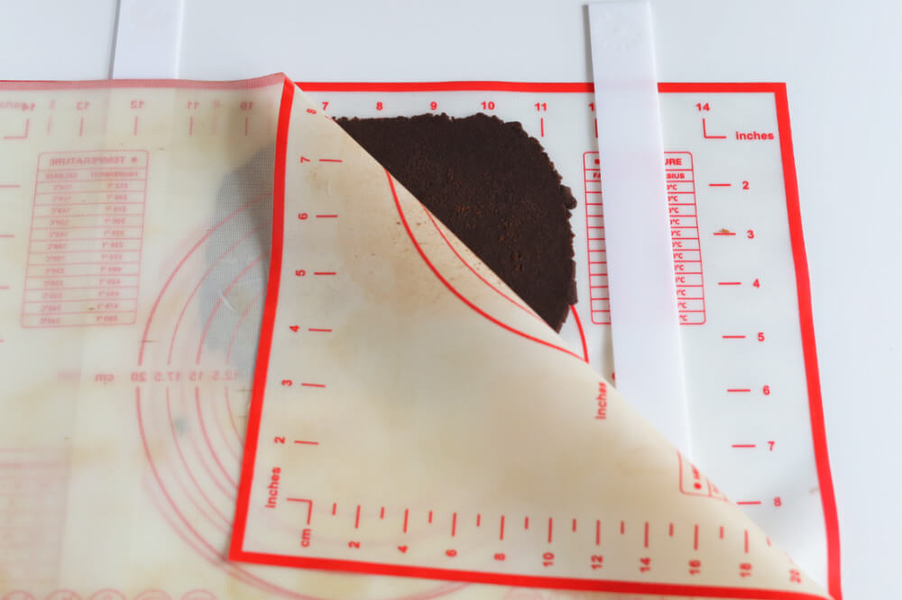 przygotowanie kakaowej kruszonki - wałkowanie pomiędzy matami silikonowymi, z użyciem listew dystansowych