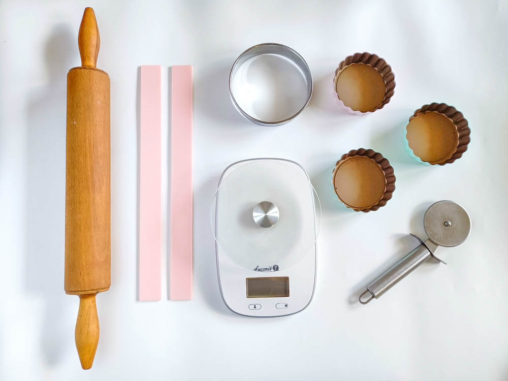 narzędzia potrzebne do przygotowania tartaletek - wałek do ciasta, listwy dystansowe, okrągły wykrawacz, waga kuchenna, radełko, formy na tartaletki z wyjmowanym dnem
