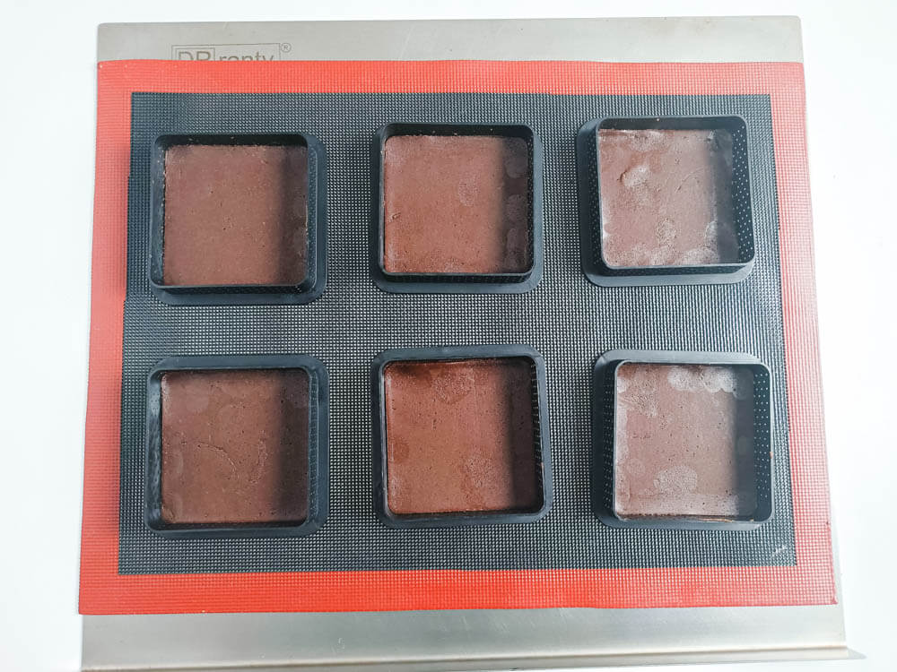 Wylepianie kwadratowych rantów perforowanych ciastem kakaowym.