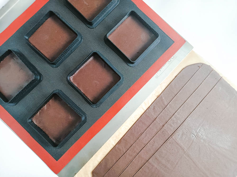 Wylepianie kwadratowych rantów perforowanych ciastem kakaowym.