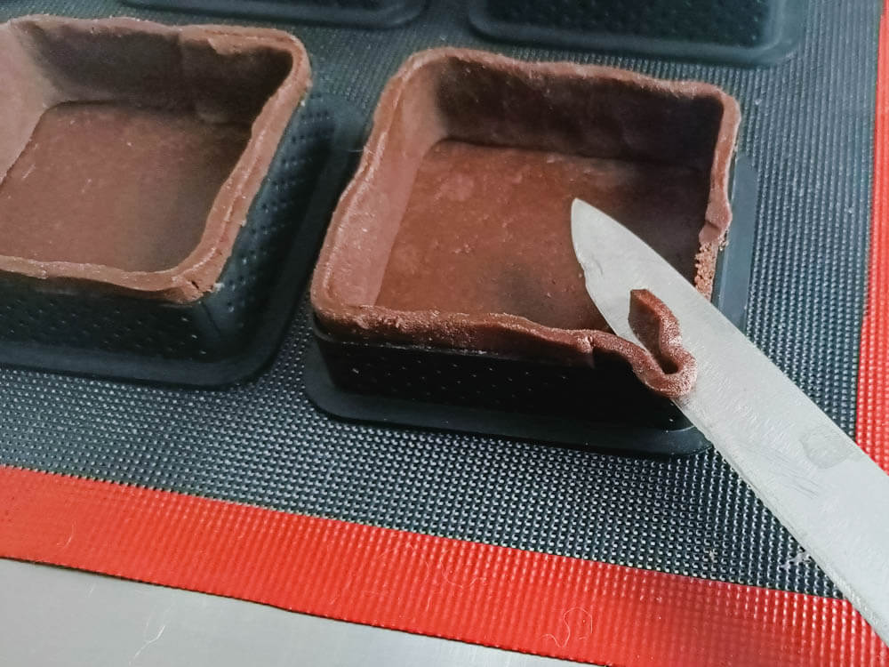 Wylepianie kwadratowych rantów perforowanych ciastem kakaowym.